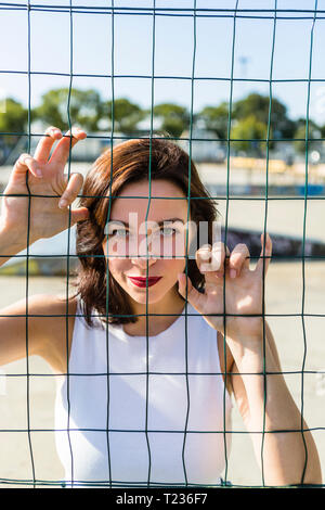 Porträt der jungen Frau hinter Zaun Stockfoto
