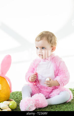 Cute kid in rosa Flauschige kostüm Holding bunte Wachteleier isoliert auf weißem Stockfoto