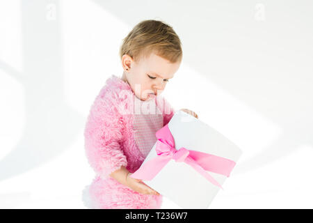 Adorable Kind in rosa Flauschige Kostüm holding Geschenkkarton mit rosa Schleife isoliert auf weißem Stockfoto