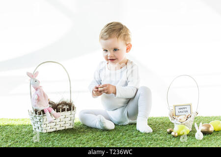 Freundliche Kinderbetreuung in der Nähe von Stroh Körbe mit Ostereiern, dekorative Kaninchen und frohe Ostern Karte isoliert auf weißem Stockfoto