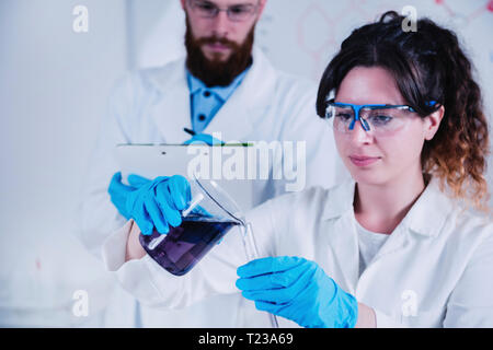Junge Wissenschaftler Experimente im Labor, das Tragen von Schutzausrüstung. Stockfoto
