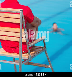 Rettungsschwimmer, sitzen im Stuhl über Swimmingpool. Stockfoto