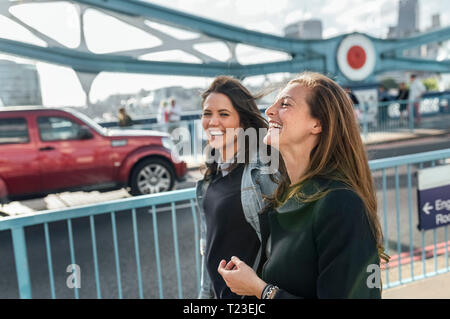 UK, London, zwei glückliche Frauen zu Fuß auf der Tower Bridge Stockfoto