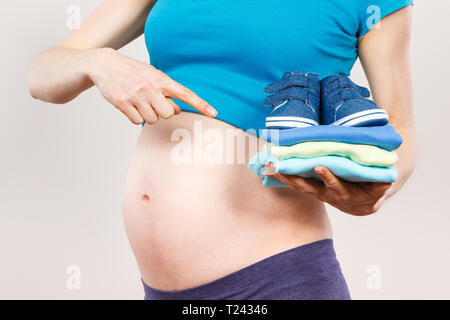 Die Frau in der Schwangerschaft übersicht Kleidung für Baby, Konzept der Ausdehnung der Familie und erwarten für Neugeborene Stockfoto