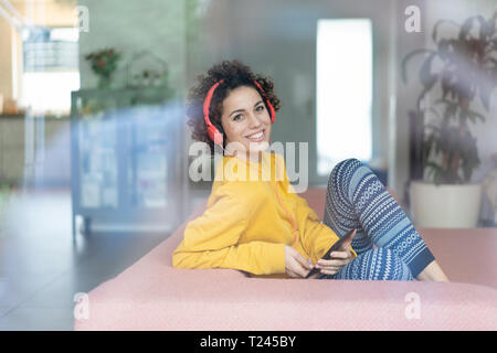 Glückliche Frau an Musik auf der Couch zu Hause Stockfoto
