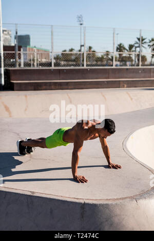 Barechested muskulösen Mann tun Push-ups in einem Skatepark Stockfoto