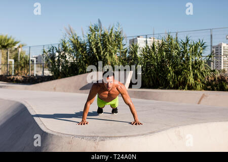 Barechested muskulösen Mann tun Push-ups in einem Skatepark Stockfoto