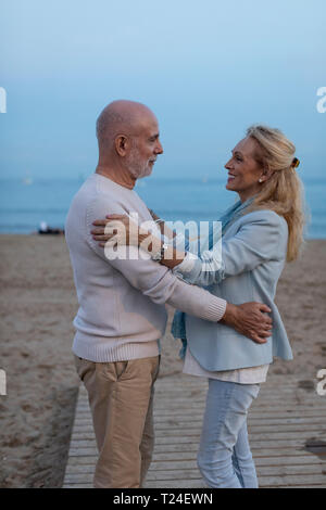 Spanien, Barcelona, gerne älteres Paar umarmt am Strand bei Sonnenuntergang Stockfoto