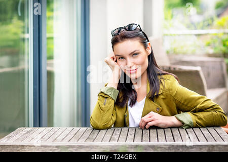 Porträt einer jungen Frau mit Sonnenbrille im Haar, Sitzen am Tisch im Freien Stockfoto