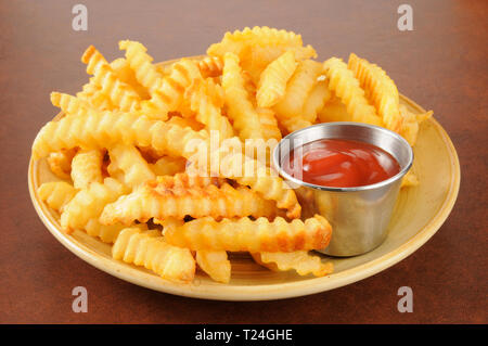 Crinkle cut Pommes frites und eine Tasse catsup Stockfoto