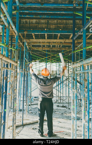 Techniker oder Meister mit Blueprint in Gebäude Baustelle. Er drücken Sie seine Hände bis zum Erfolg auf den Aufbau Baustelle. Stockfoto