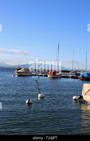 Die schöne Landschaft in der malerischen Altstadt von Nyon, Schweiz fotografiert. Auf diesem Foto sehen Sie einen See, blauer Himmel mit einigen Wolken, Boote & Bojen. Stockfoto