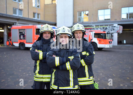 Portrait von drei zuversichtlich Feuerwehrmänner stehen auf Hof vor Fire Engine Stockfoto