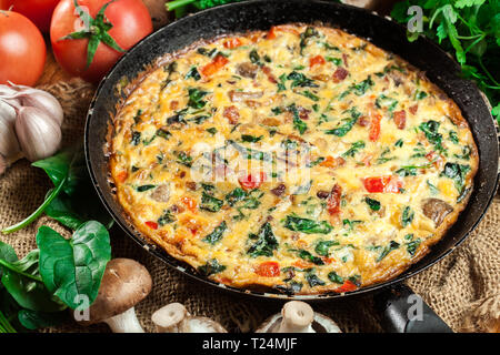 Frittata aus Eiern, Pilzen und Spinat auf der Pfanne. Italienische Küche Stockfoto