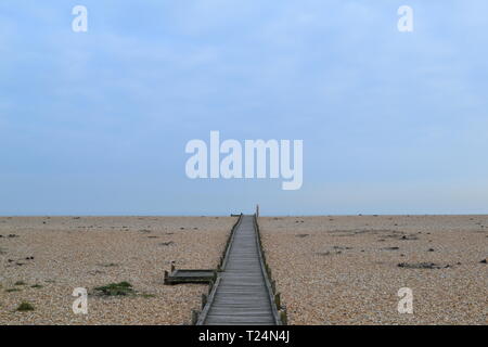 Die Promenade zum Meer über den Kies in Dungeness, Kent, Großbritannien, ein Naturschutzgebiet führt. Am anderen Ende der Promenade ist das Britannia Inn Stockfoto