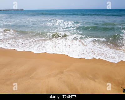 Wellen mit weißen Meer Schaum auf einem sandigen Strand bei Ebbe in Lagos, Nigeria. Schöner Blick aufs Wasser des Atlantiks mit kopieren. Stockfoto