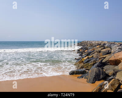 Wellen plätschern auf Felsen in einen wellenbrecher an einem sonnigen Tag am Strand. Schutz der Küstengebiete und der Küste Befestigungsanlage. Stockfoto