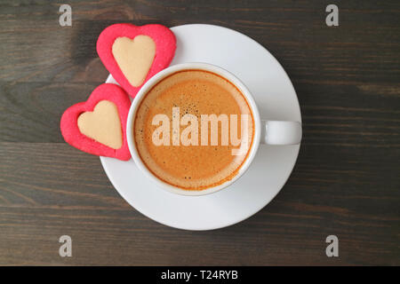 Flach Foto von einer Espressomaschine mit zwei herzförmige Plätzchen auf dunkelbraunen hölzernen Tisch serviert. Stockfoto