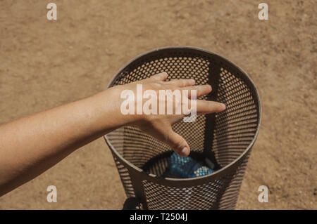Hand der Frau werfen eine Plastikflasche in einem Mülleimer auf einen Park in Merida. Die Stadt bewahrt viele Gebäude des antiken Roms in Spanien. Stockfoto