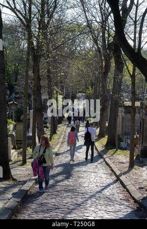 Touristen zu Fuß zwischen den Gräbern entlang einer Gasse am Friedhof Pere Lachaise, Paris, Frankreich Stockfoto