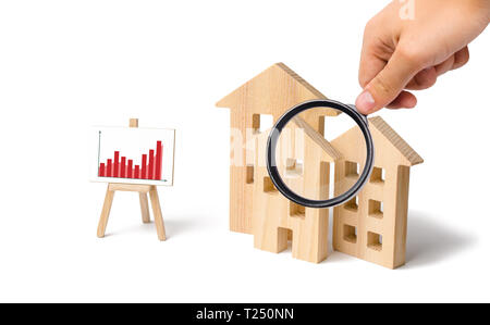 Lupe schaut sich die Holzhäuser mit einem Stand von Grafiken und Informationen. Wachsende Nachfrage nach Wohnungen und Immobilien. Statistiken über t Stockfoto