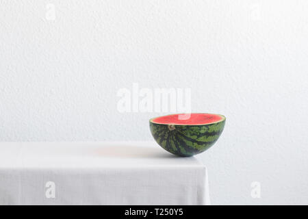 Die Hälfte der Wassermelone auf einem weißen Tisch mit kopieren. Kreative noch Leben Stockfoto