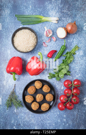 Bestandteile einer falafel jambalaya Rezept. Blick von oben auf die Reis in einem dunklen Schüssel, falafels auf einem dunklen Platte, Tomaten, corianders, Chili, Paprika, auf Stockfoto