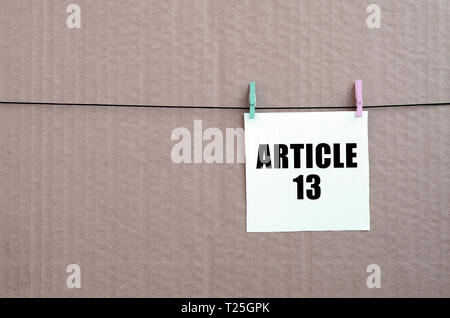 Artikel 13 Die Aufschrift am weißen Karte am Seil auf einem braunen Karton Hintergrund. Die europäische Richtlinie zum Urheberrecht einschließlich Artikel 13 wird durch das Europea genehmigt Stockfoto