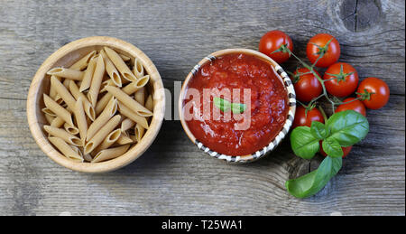 Konzept der italienischen Küche. Italienische Tomatensauce mit Basilikum und Vollkornpasta auf Holzhintergrund.Draufsicht Stockfoto