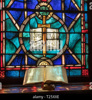 Licht vom Fenster aus buntem Glas fällt auf offene Bibel in der amerikanischen Kirche Stockfoto