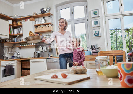 Glückliche Mutter und Tochter Backen Pfannkuchen in der Küche zu Hause zusammen Stockfoto