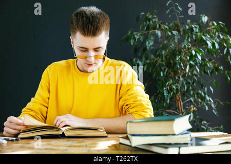 Blonde Studentin in Brille gelb Pullover, der seine Hausaufgaben in der Klasse Stockfoto