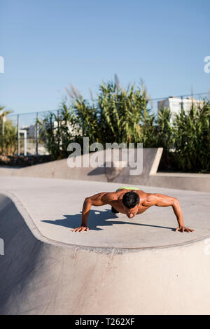 Barechested muskulösen Mann tun Push-ups in einem Skatepark Stockfoto