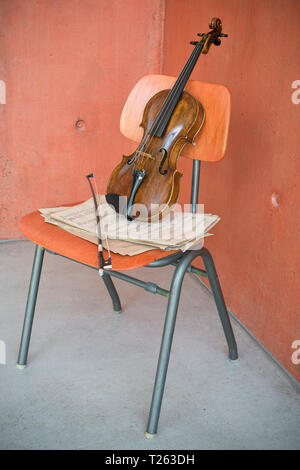 Violine, Bogen und Noten auf hölzernen Stuhl Stockfoto
