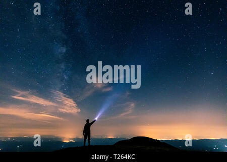 Italien, Monte Nerone, Silhouette eines Mannes mit Lampe unter Nachthimmel mit Sternen und der Milchstraße Stockfoto