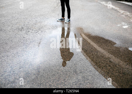 Reflektion von einem Mann in einer Pfütze auf dem Boden Stockfoto