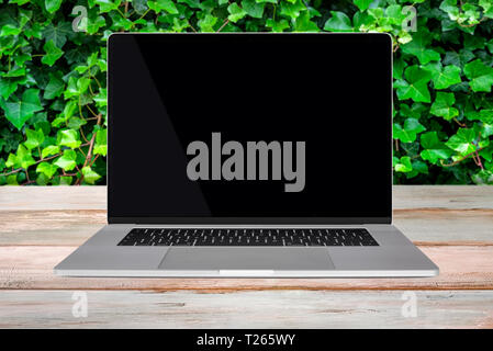 Grün umweltfreundliche Umwelt Vorlage - Vorderansicht eines generischen modernen Laptop mit einem schwarzen Bildschirm auf Holztisch (Kopie). Stockfoto