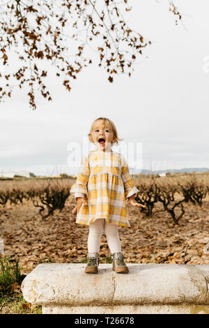 Kleines Mädchen schreiend auf einer Parkbank Stockfoto