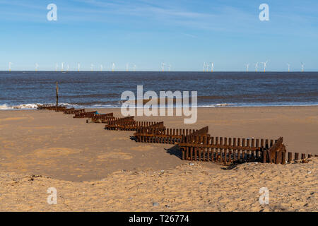 Nordsee küste in Caister-on-Sea, Norfolk, England, Großbritannien - mit einer Welle Leistungsschalter und Windenergieanlagen im Hintergrund Stockfoto