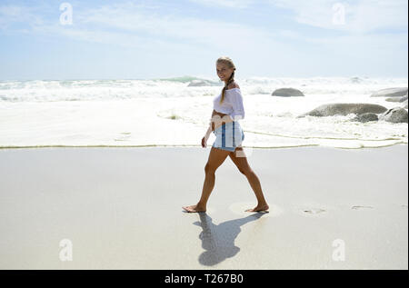 Lächelnd schwangere Frau zu Fuß am Strand Stockfoto