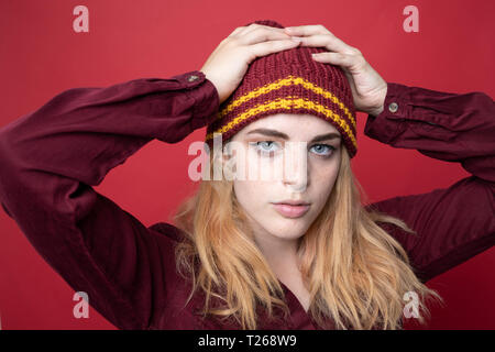 Porträt der jungen Frau mit Wooly hat vor rotem Hintergrund Stockfoto