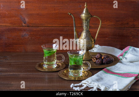 Iftar und Suhoor Ramadan Konzept, Mentha Kaffee auf Glas Tassen und Termine auf Holz- Hintergrund mit einem alten Teekanne Stockfoto