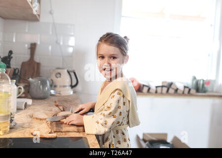 Portrait von Lachen kleines Mädchen schneiden Brot in der Küche Stockfoto