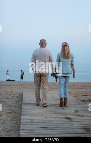 Spanien, Barcelona, Rückansicht des Senior paar Hand in Hand am Strand bei Sonnenuntergang Stockfoto