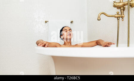 Junge Frau liegend in der Badewanne mit ihren Augen zu Hause geschlossen Stockfoto