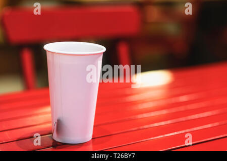 White Paper Cup mit Tee Pocket auf dem roten Tisch Stockfoto