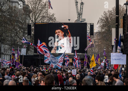 Tommy Robinson sprechen auf der Bühne des Brexit Verrat Protestkundgebung in Whitehall, Westminster, London, UK, mit Masse und Union Jack Flags Stockfoto