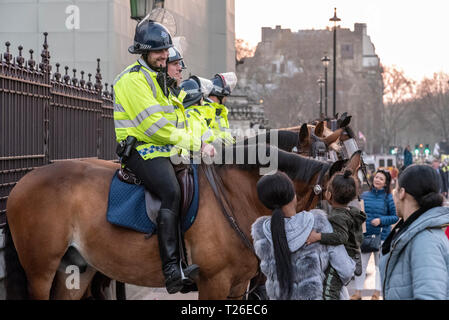 Berittene Polizei in Westminster, London, UK, während der Brexit Verrat Rallye mit Mutter und junges Mädchen, die Aufmerksamkeit auf ein Pferd. Lächelnd Polizei Stockfoto