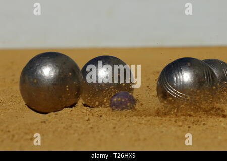 Ein französisches Boule im Augenblick des Aufpralls verursacht eine kleine Explosion von Sand auf Le erfasst aber Stockfoto