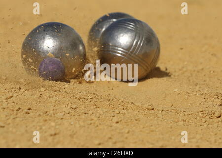 Ein französisches Boule im Augenblick des Aufpralls verursacht eine kleine Explosion aus Sand erfasst Stockfoto